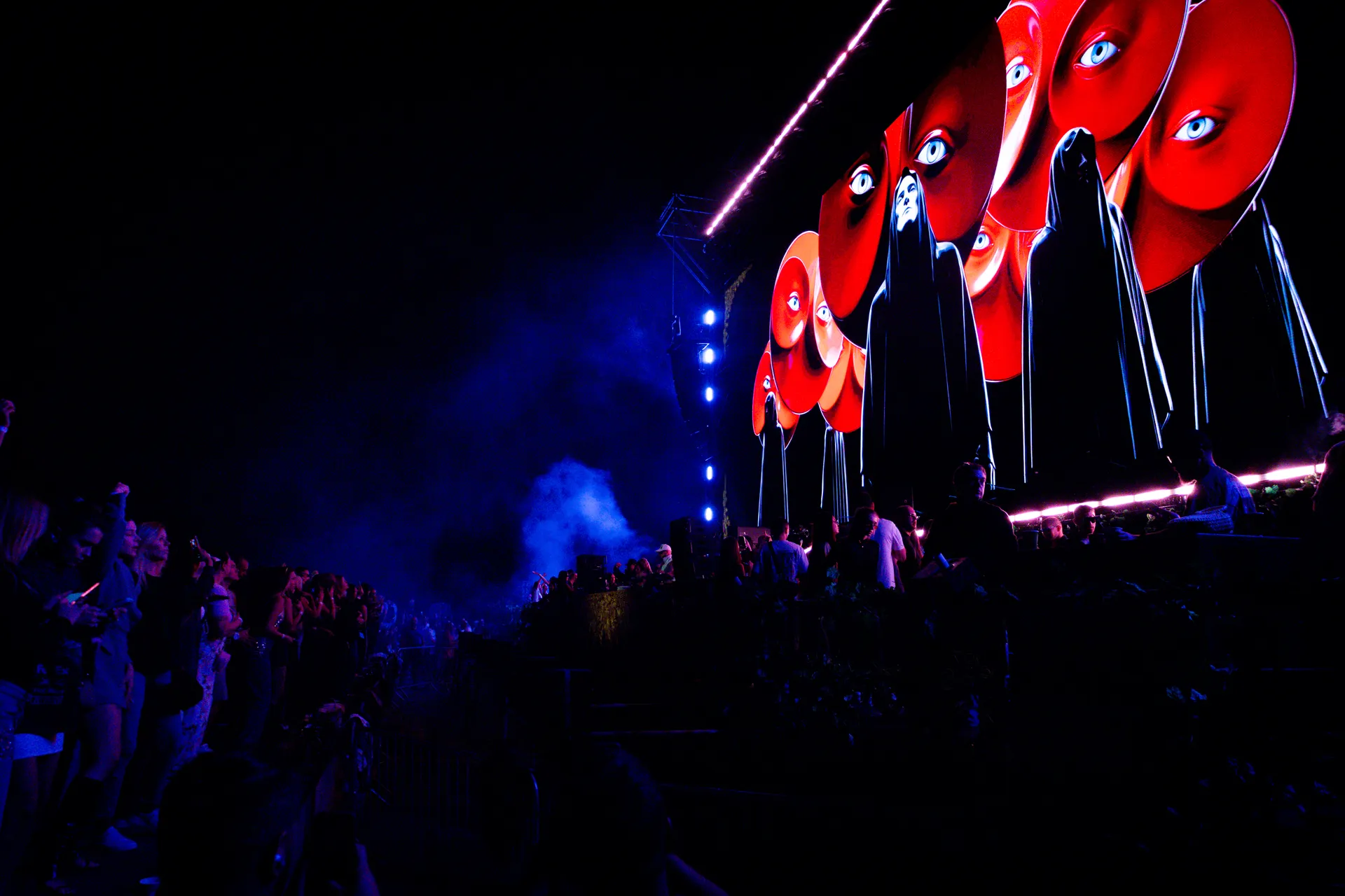 Awakening of Eras — surreal red-eye and hooded figures on the LED wall