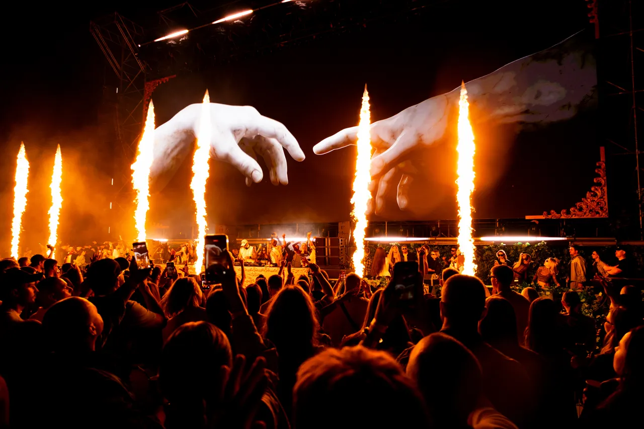 Audience filming flame jets and LED art on their phones